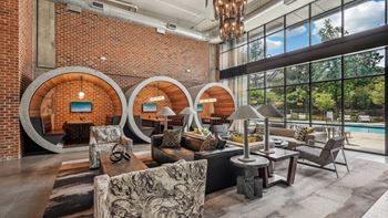 Resident clubhouse with many seating areas with couches, work booths, and chairs with a pool view